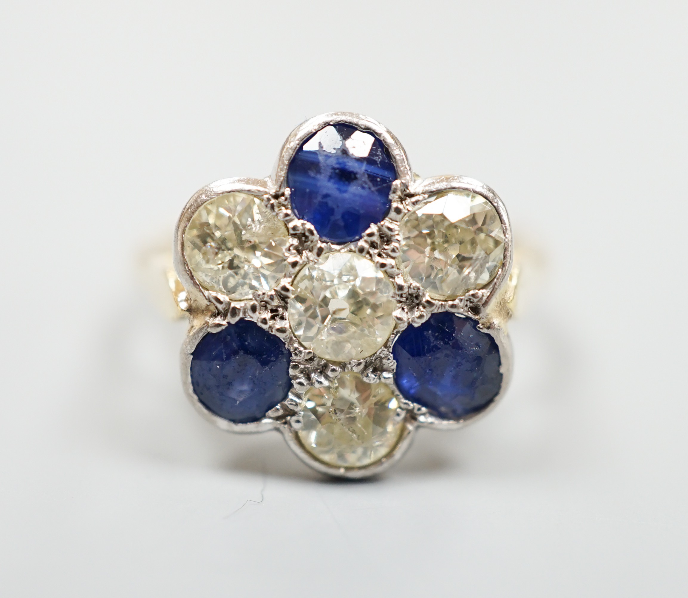 A modern 18ct gold, four stone diamond and three stone sapphire set flower head cluster ring, size J, gross weight 4.1 grams.